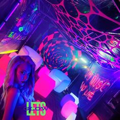 a woman standing under an umbrella in a room with neon colored lights on the ceiling