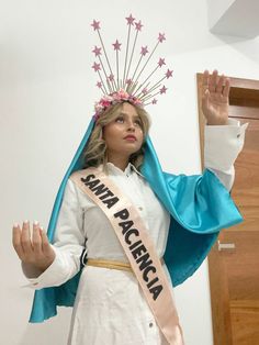 a woman wearing a crown and holding her hands up in the air while standing next to a door