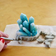 a person is using a paintbrush to decorate something blue and white on a piece of paper