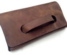 Original Style. Superior Quality. American Made. One of the coolest designs around. Our sleek and modern clutch is perfect for day or night. The handle makes it quite comfortable to hold on to and there is plenty of room inside. This bag makes carrying a clutch comfortable. *Made from unlined high quality American leather *Measures 10 inches by 5.5 inches (25.5 cm by 14 cm) *Hand sewn Our distressed brown leather scuffs very easily, this means out of the box it will look worn in. That gives it a Modern Clutch, Clutch Pattern, Brown Leather Clutch, Leather Anniversary, Bags Leather Handbags, Leather Card Wallet, Unique Purses, Handcrafted Bags, Black Leather Purse