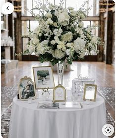 a table topped with white flowers and pictures next to framed photos on top of it