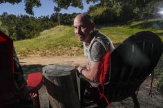 a man sitting in a chair next to a tree stump