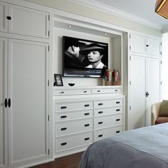 a bedroom with white cabinets and a flat screen tv mounted on the wall above it