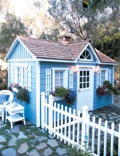 a small blue house with white picket fence