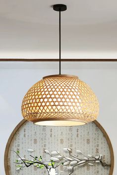 a white vase sitting on top of a wooden table next to a light hanging above it