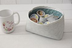 a coffee cup and mug holder on a white counter top next to a tea bag