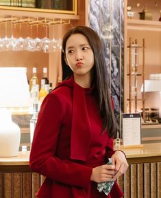 a woman standing in front of a counter wearing a red coat