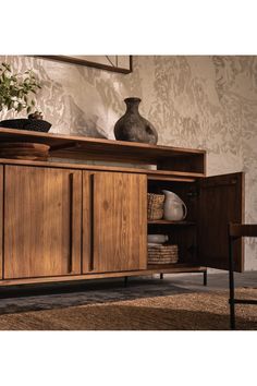 a wooden cabinet sitting in front of a wall with a vase on top of it