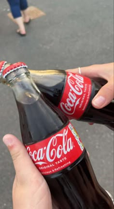 a person holding up a bottle of coca cola