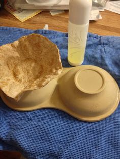 a bowl with a tortilla in it on a blue towel next to a bottle