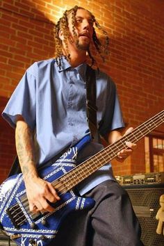 a man with dreadlocks playing an electric guitar