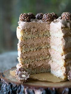 a piece of cake with chocolate and raspberries on top sitting on a tree stump