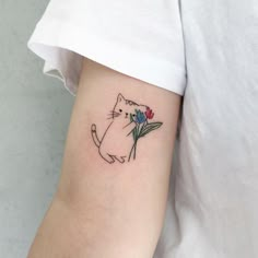 a cat with flowers on its arm is shown in this tattoo design by the artist