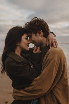 a man and woman embracing each other on the beach