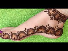 the foot is decorated with henna and flowers on top of green carpeted ground