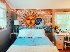 a bedroom with a sun and moon mural on the wall above the bed, next to a window