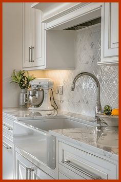 a kitchen with white cabinets and marble counter tops