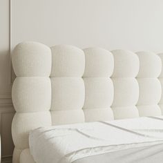 an upholstered headboard on a bed with white sheets