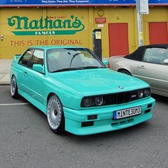 a blue car is parked in front of a building with a sign that says nathan's famous