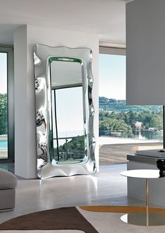 a living room filled with furniture and a large mirror on the wall next to a window