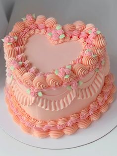 a heart shaped cake with pink frosting and flowers