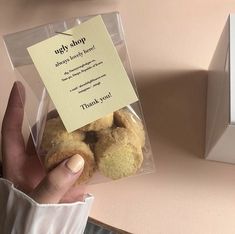 a person holding a package of donuts in front of a box with a note on it