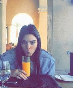 a woman sitting at a table with a glass of orange juice