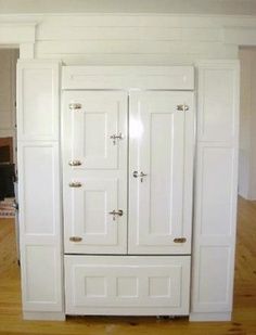 a tall white cabinet sitting on top of a hard wood floor