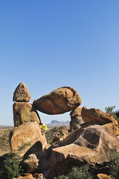 a man climbing up the side of a large rock formation on top of a mountain