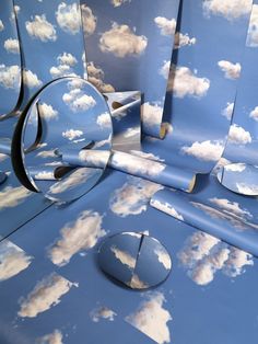 blue sky with white clouds and round mirrors on the floor in front of an array of wallpapers