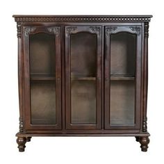 a wooden cabinet with glass doors and carvings on the front, sitting against a white background