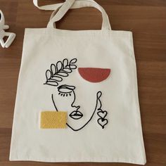 a tote bag with an embroidered face on it