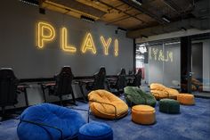 an office with chairs and neon signs on the wall, in front of a blue carpeted floor