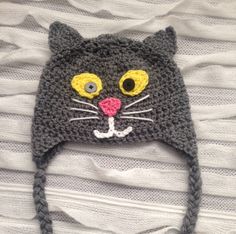 there is a crocheted cat hat on top of a white sheet with yellow eyes