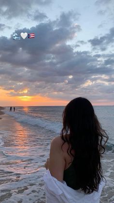 a woman standing on top of a beach next to the ocean