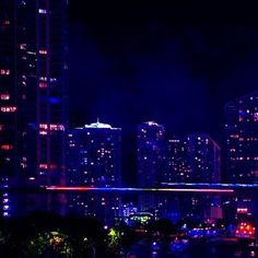 the city skyline is lit up at night with bright lights and skyscrapers in the background