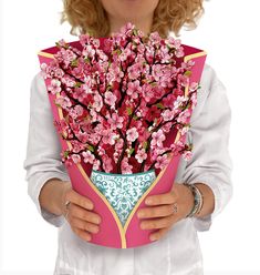 a woman holding a bouquet of pink flowers in her hands and wearing a white shirt