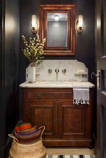 a bathroom with a sink, mirror and basket on the floor in front of it