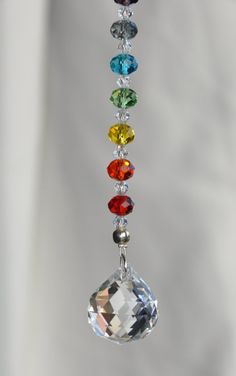 a multicolored glass beaded mobile hanging from a hook on a white wall