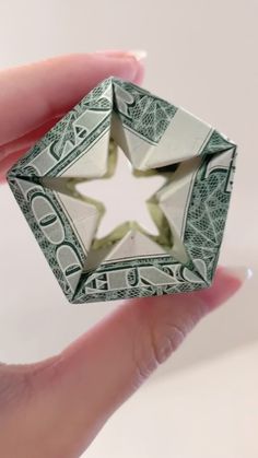 a hand holding a dollar bill origami piece in it's palm,