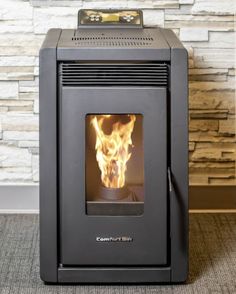 a wood burning stove in front of a brick wall with a fire coming out of it