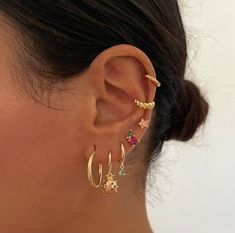 a close up of a person's ear with three different colored stones on it