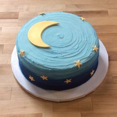 a cake with blue icing and yellow stars on the top is sitting on a wooden table