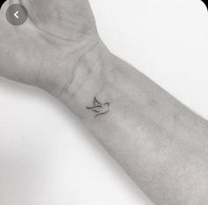 a person's arm with a small bird tattoo on the left side of their wrist