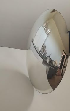 the reflection of a building in a round mirror on a white surface with a black handle