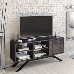 an entertainment center with a flat screen tv on it's stand, in front of a brick wall