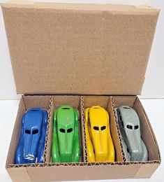 four toy cars are in a cardboard box