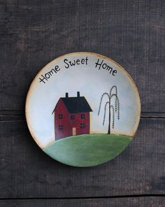 a plate with a red house on it that says home sweet home and two windmills in the background