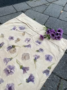 purple flowers are laying on the ground next to a piece of paper that has been torn off