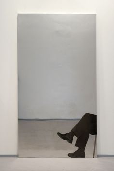 a person sitting on a chair in front of a white wall with an open doorway